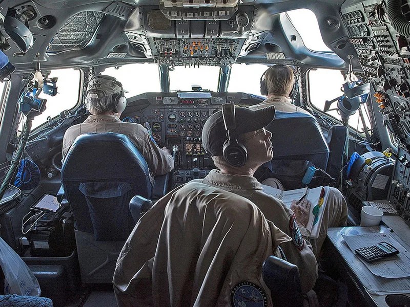 Three people in aircraft cockpit.