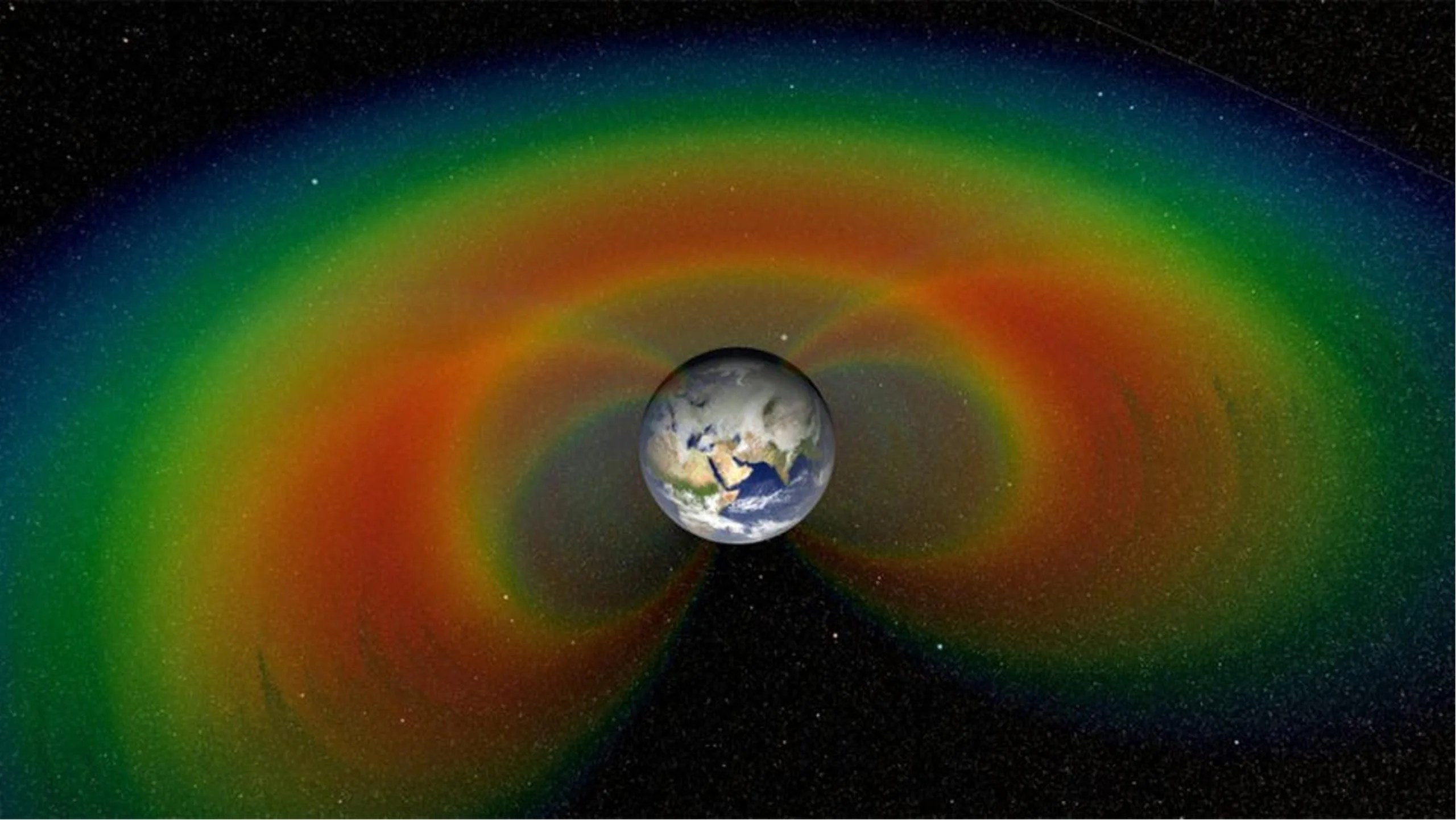 The Earth is centered against a starry universe. Several rainbow-colored bands surround the Earth in oblong and spherical shapes.