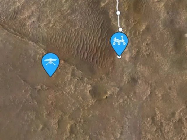A zoomed in view of the surface of Mars. Two blue ice cream cone-shaped location icons are shown, one with a helicopter symbol on it and the other with a rover symbol.