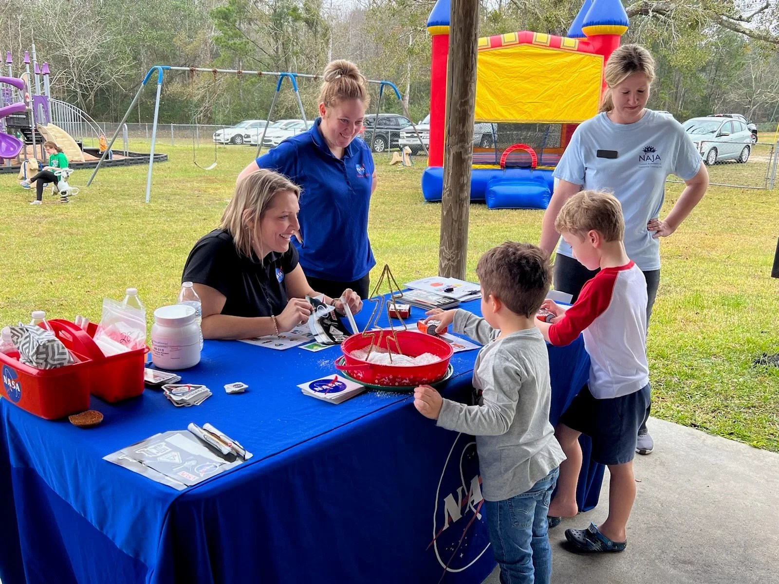 NASA ACCP team members (Morgan Necaise (l) and Kallie Crowell (r) teach children with autistic diversabilities about polymer science and robotics at the Winter Sensory Celebration hosted by Hancock County Junior Auxiliary on December 10th, 2022.