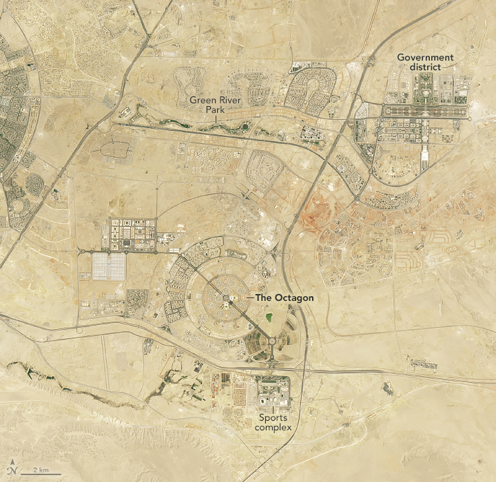 Amid the bright beige landscape there are roads with central zones in the top right, and image center, where more roads extend from radially and ring around a dark spot labelled "The Octagon" with a sports complex down below one of the major roadways from there. The other built up region is labelled the Government district, and is oriented in a cross.