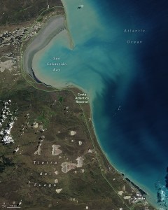 The image shows the Atlantic coastline in South America, the Ocean is seen right, in a dark blue, but the region near the coast, particularly in the upper part of the image appears significantly lighter due to suspended particles. The land appears to be mostly covered in vegetation, but is more brown than green.
