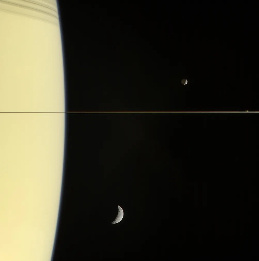 curve of saturn with several moons visible nearby