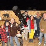 Nighttime photo of a group of people gathered around telescopes