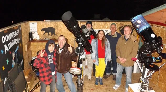 Nighttime photo of a group of people gathered around telescopes