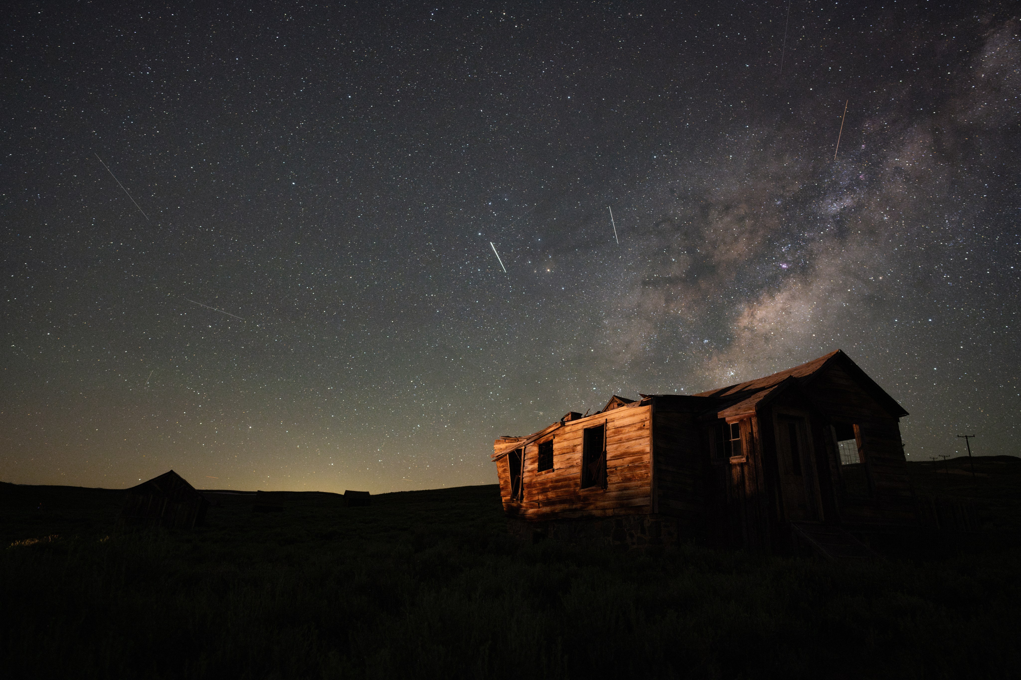 环绕轨道运行的卫星在加利福尼亚沙漠一处破败的鬼城废墟上，在昏暗的天空中发出一道光。