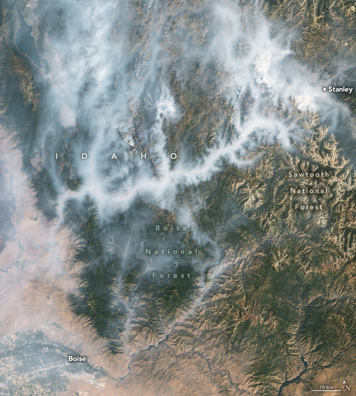 Beige colored landscape in the lower left surrounds Boise in the corner of the image. It gives way to rising mountainous regions covered in green. Interspersed in the Boise National Forest and Sawtooth National Forest are webs of smoke that seem to follow many of the Forest valleys. In the upper right corner there is a marker for town of Stanley.