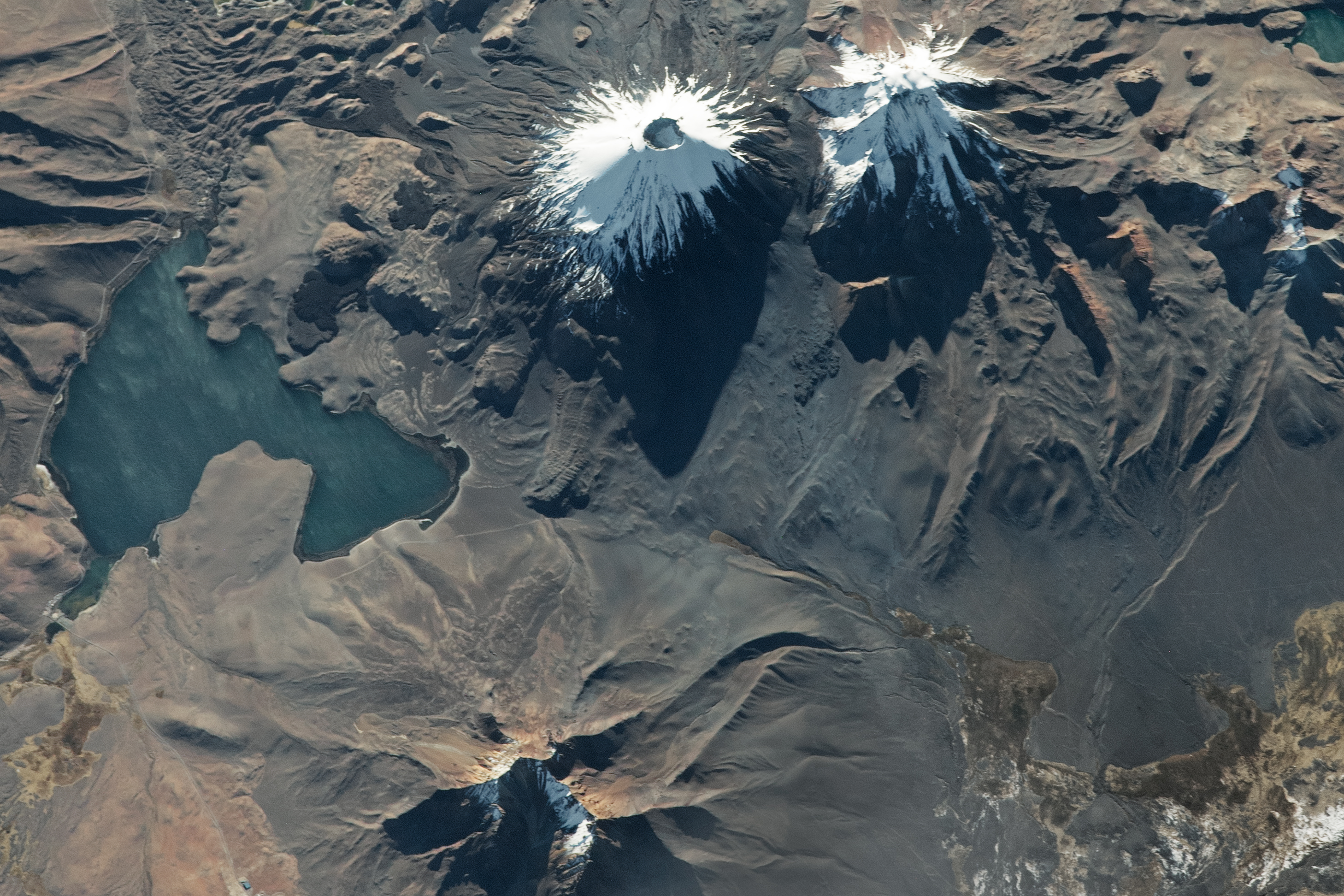 The Parinacota and Pomerape volcanoes rise like twins along the Chile-Bolivia border, but close inspection reveals distinct differences in their appearance.