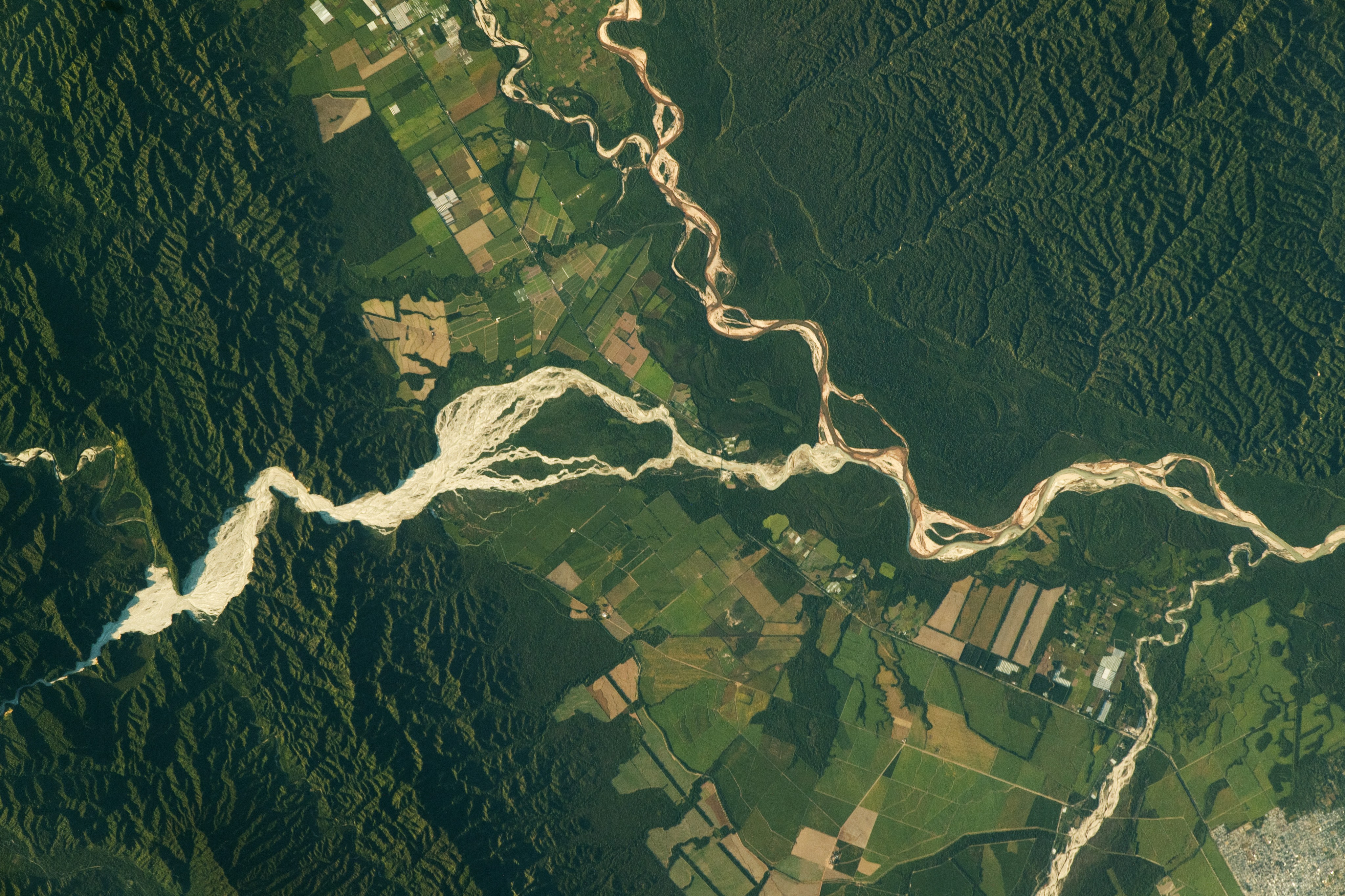 The photo shows the city of Orán (lower-right) and a small section of Aniceto Arce (top), a Bolivian province that is surrounded by the Bermejo River and Río Grande de Tarija. The meandering rivers in this image are sourced in the Andes Mountains and generally flow southeast through valleys in the foothills—the region between the high mountains and plains. The Iruya River deposits particles of silt and clay as it flows into the valley centered in this image.