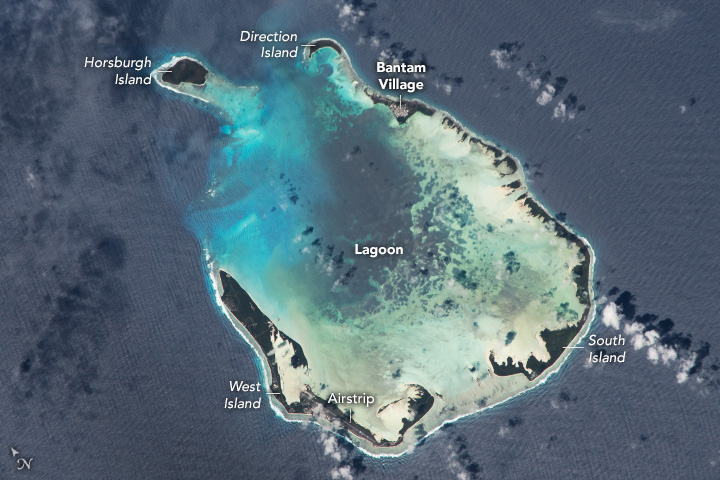 The atoll is in a U shape with the large break being to the upper left corner of the image despite there being a significant island at that end (Horsburgh) the depth drops off on that end as clearly indicated by the appearance of the water changing from reflecting the sandy bottom through the shallows at the bottom of the U to gradually more turquoise before becoming uniform to the surrounding deep ocean.