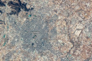 The image of Beijing from above features the Forbidden City slightly left of the image center. A moat appears on the right, diagonal to the image orientation. Numerous ring roads surround the Forbidden city and beyond the 4th ring road the landscape seems to change color from gray to beige. A lake is labelled up and left of the Forbidden City. Yongding River is on the very left center edge, just outside of the 5th ring road. In the bottom center is High-speed railway. The 6th ring road extends far out and is labelled in the upper right corner. The Airport and Wenyu River appear to be mostly inside the 6th ring road