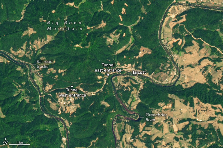 Lush, green mountainous landscape, with Big Bend Mountain at the top of the image. A river runs down the left side of the image, along with some Railroad tracks. Greenbrier River Meanders vertically along the right side of the image with farm fields appearing common to the right side of the river. Centered in the image are points for the west tunnel west and east entrance. To the right of the tunnels is the town of Talcott.