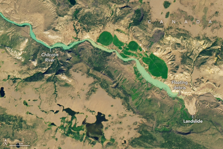 A seafoam green river stretches from the top left to the lower center right. The river appears to be completely blocked by a mass of light brown land in it's path and cuts into the otherwise green landscape on that side of the river.