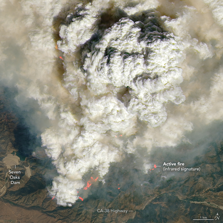 grey to sand colored clouds billow and occupy most of the image. The bottom of the image is the only area where land can be seen. In the bottom left Seven Oaks Dam is labeled. In the bottom center CA 38 Highway is labeled. Slightly above the highway orange flames are visible and in the bottom right an orange spot is labeled an Active fire.