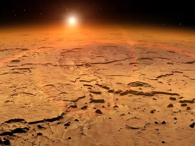 A reddish brown pockmarked surface is shown with a hazy orange glow emanating from its upper limb. A bright yellow-white circle hovers above the surface.