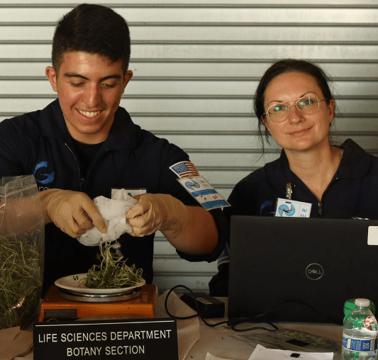 Photo of a man and woman weighing the microgreens they harvested from a parabolic flight experiment.