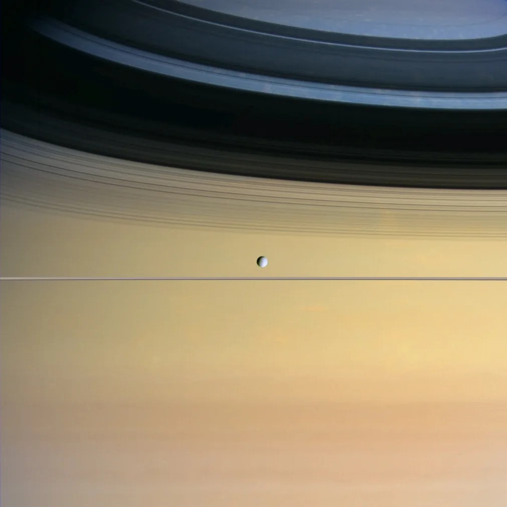 moon floating before immense face of Saturn