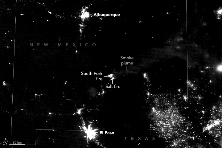 A dark image that shows light being emitted from Earth's surface is focused on New Mexico. The Cities of El Paso and Albuquerque are vibrant with sporadic town lights along major roadways. There are two lights coming from fires in the center of the image.