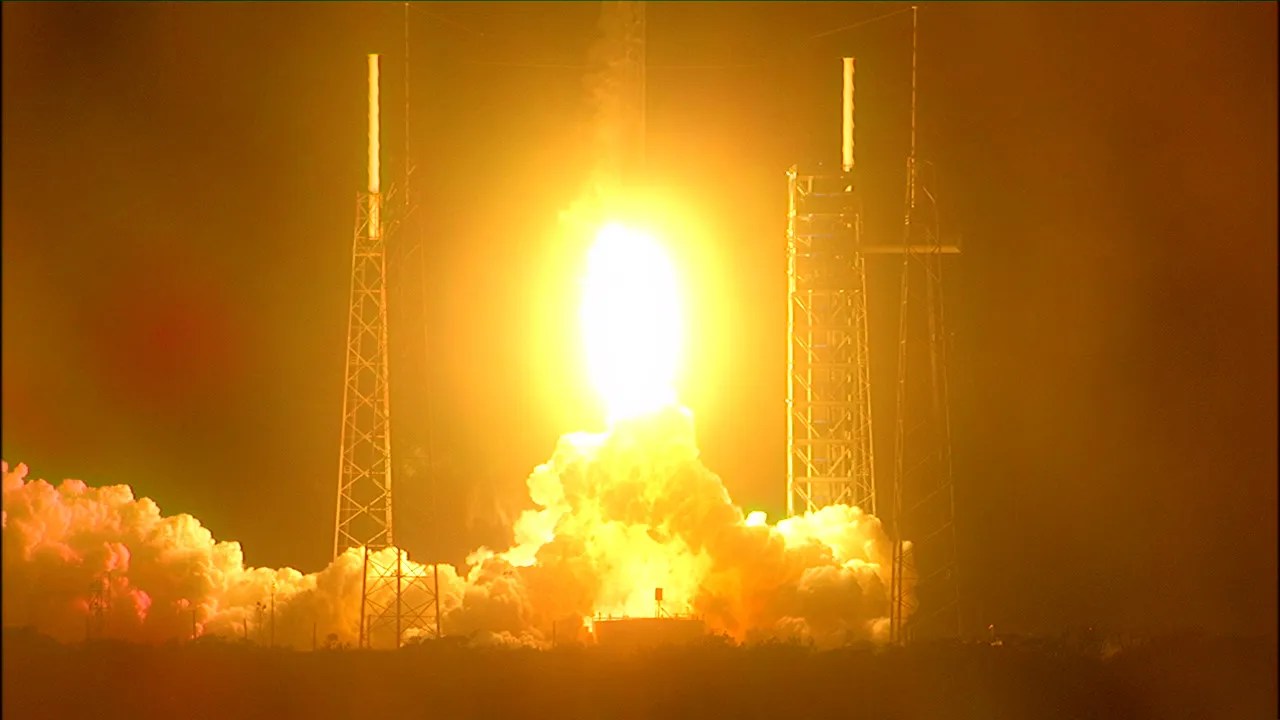 glowing yellow orb of rocket exhaust centers, illuminating nearby launch towers at night