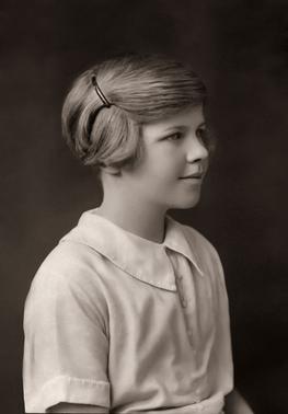 Black and white photo of a young girl with a spiral bun in her hair.