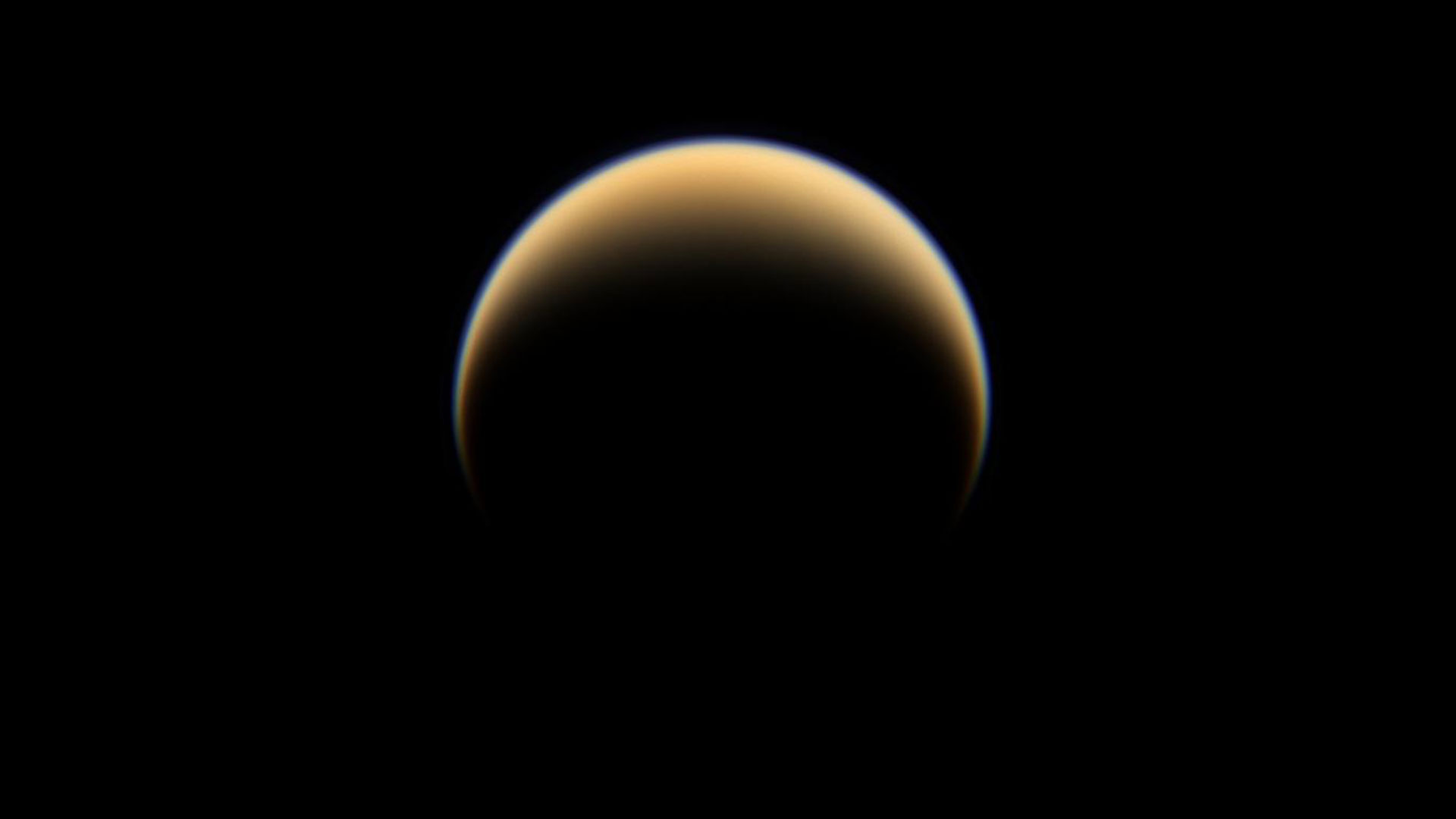 Hazy, yellowish Titan against the darkness of space