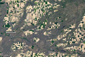 aerial image of rural Washington state show numerous darkened valleys with sprawling tributaries densely packed across a region dotted with circles and squares of different farmland