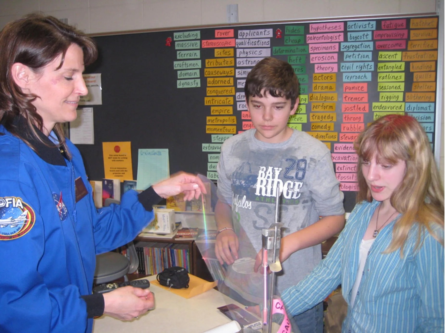 Teacher wearing blue NASA jacket in lab classroom with two students