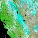 A false color satellite image of California where snow is highlighted light blue. The Eastern portion of the state shows a significant degree of snow coverage and to the west the land is a vibrant green.