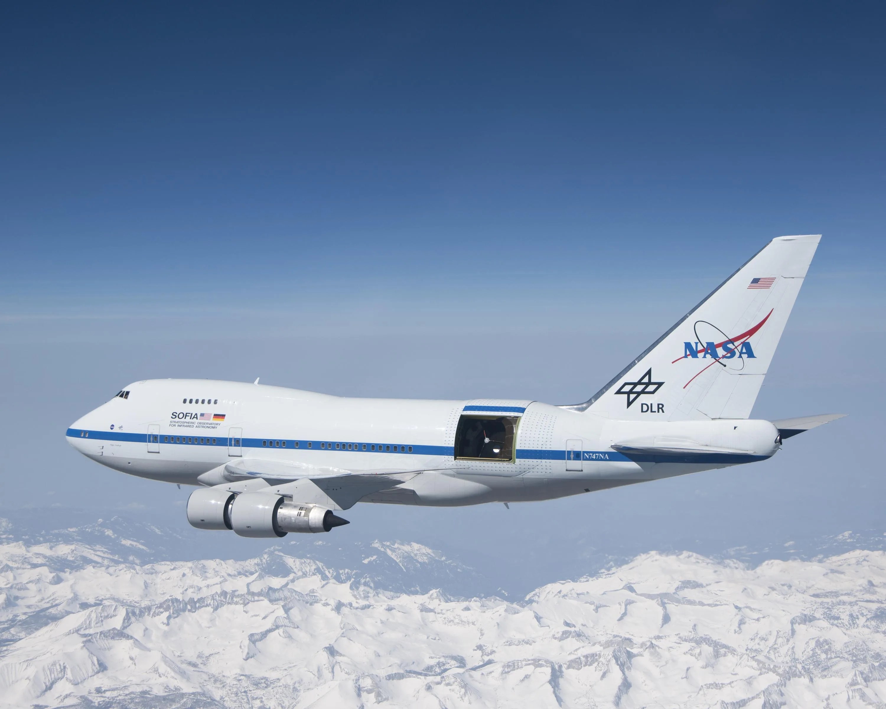 SOFIA soars over the snow-covered Sierra Nevada mountains with its telescope door open during a test flight.