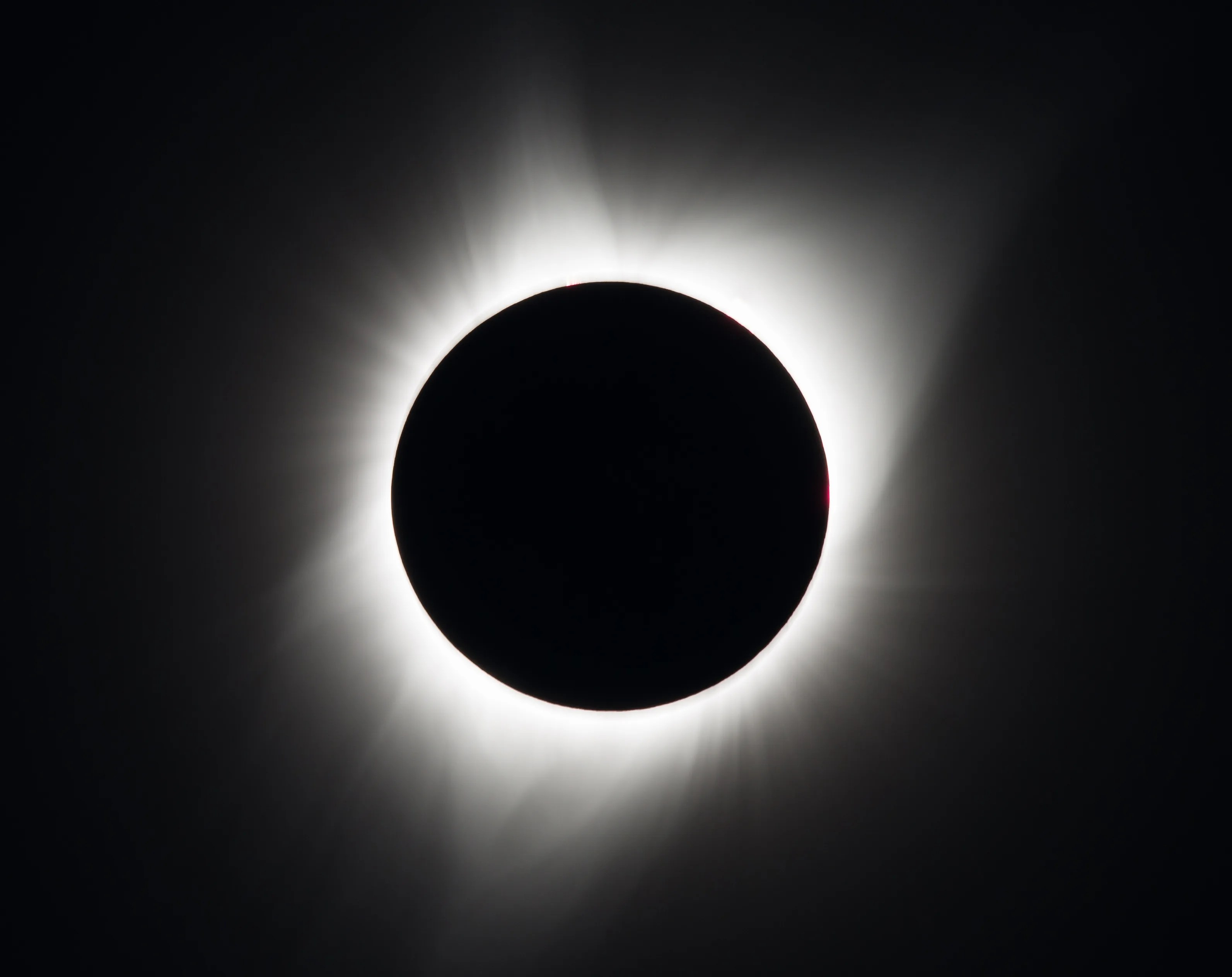 太阳微弱的白色日冕从月亮黑色的圆形轮廓后面向外窥视