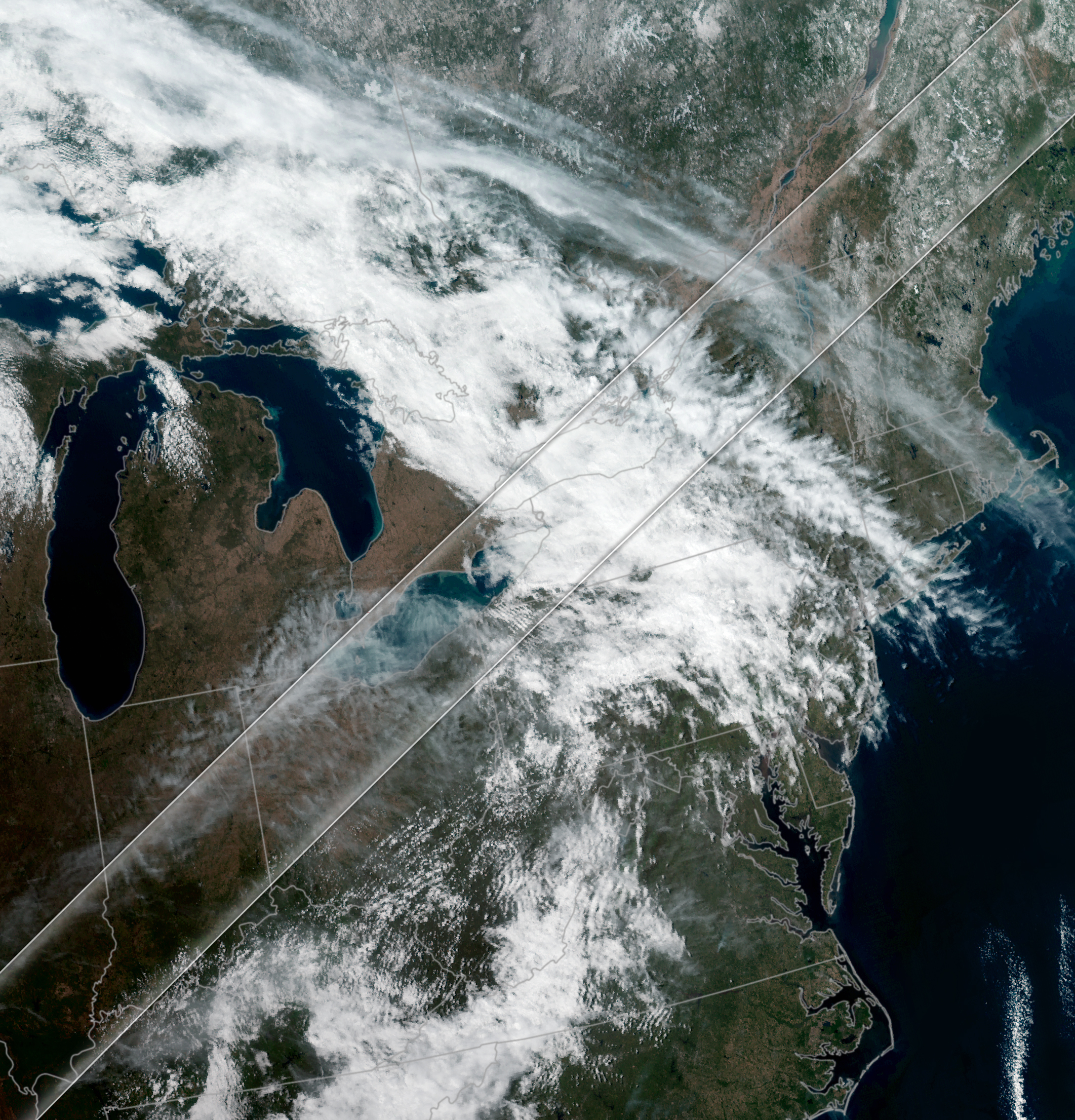 Cloudy satellite view of the northeastern and northern Midwest of the united states with an overlay of the recent solar eclipse path denoted by two parallel lines.