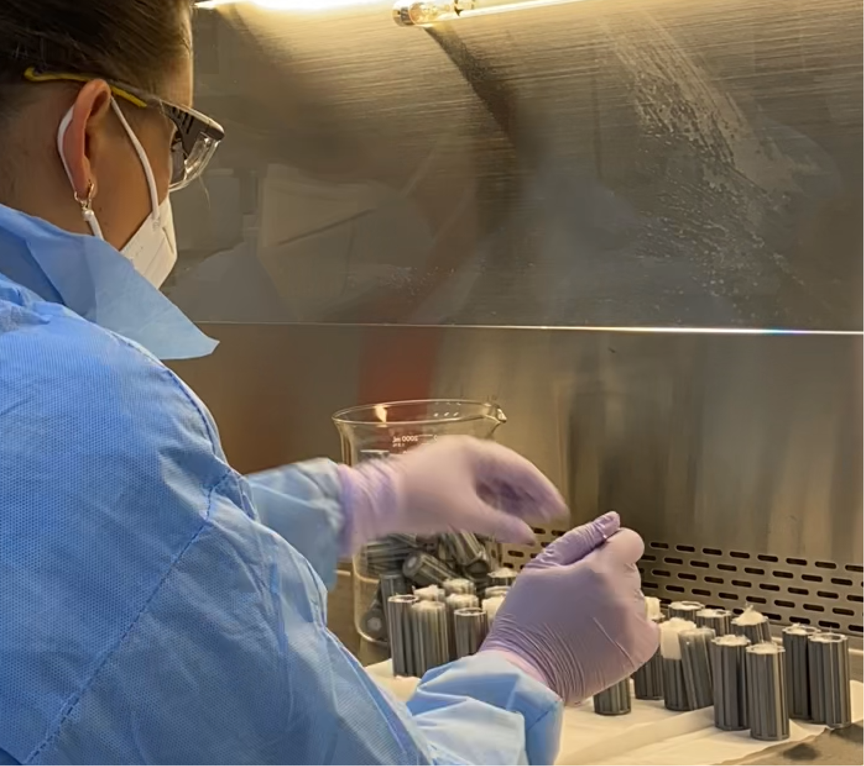 Scientist fills small cylinders with samples of soil and microbes.