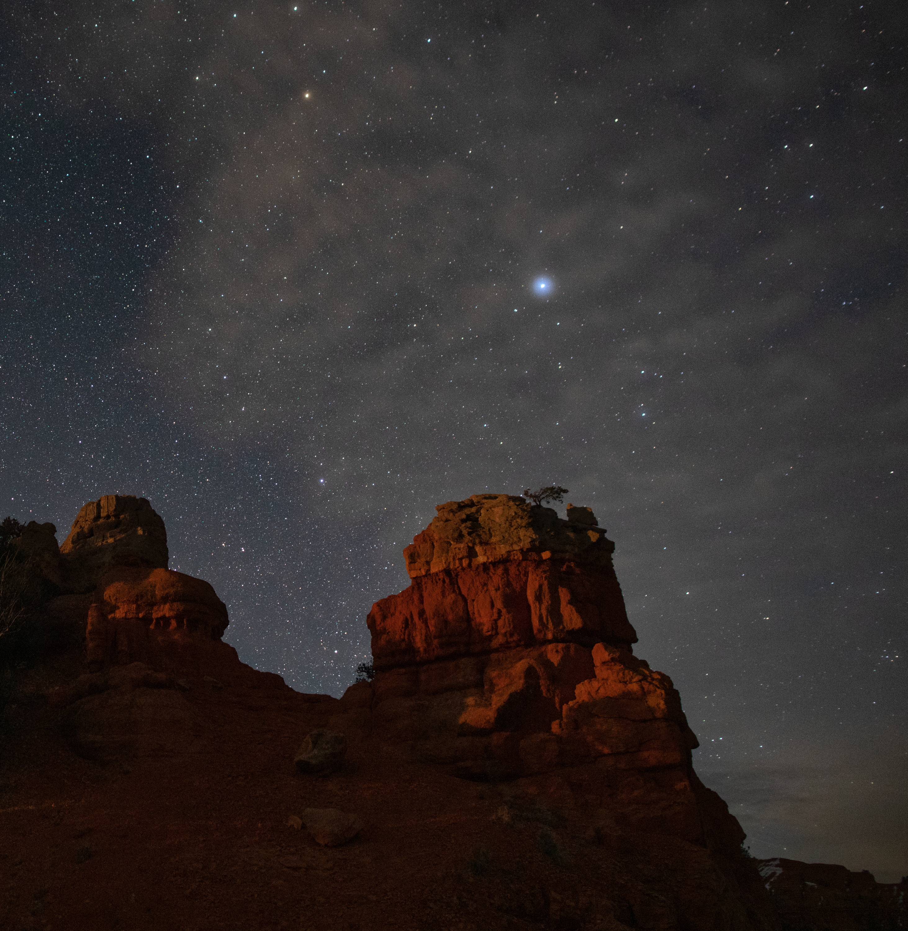 A crisp sky filled with stars frames two craggy desert peaks.
