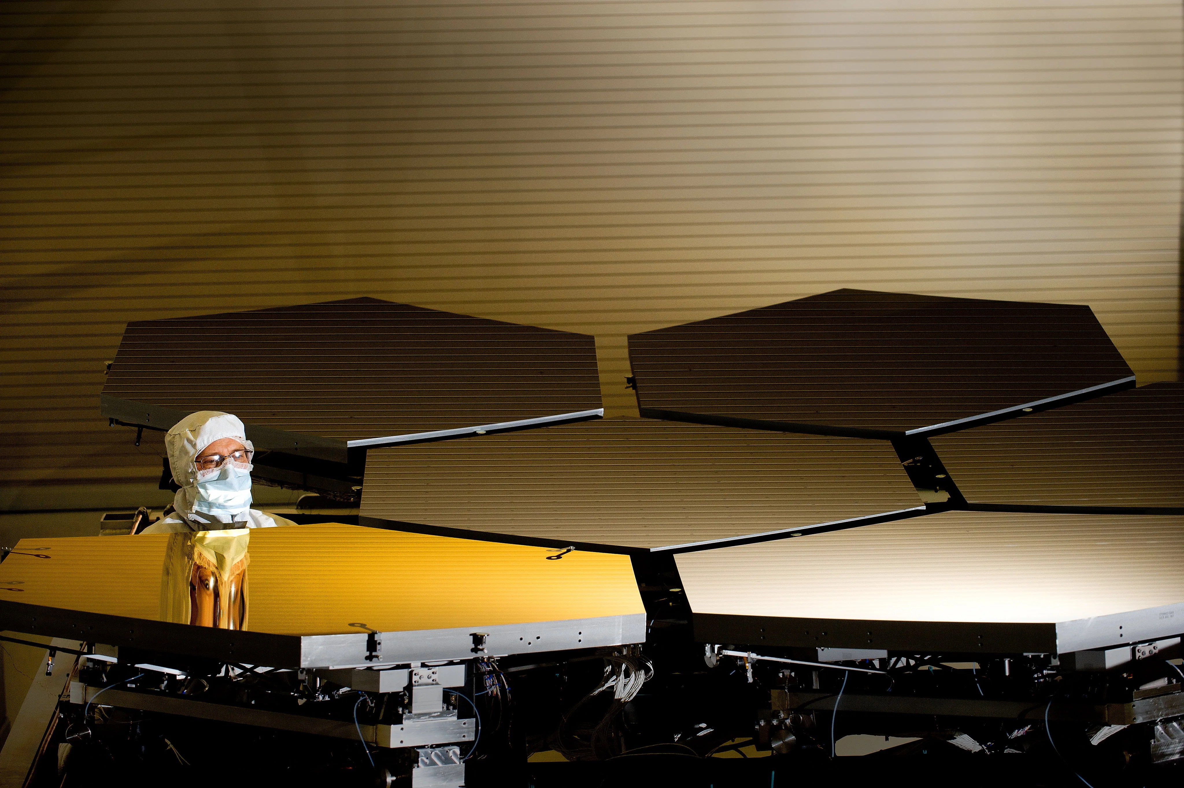 An engineer over looks the Gold-coated Primary Mirror Segment of the James Webb Telescope.