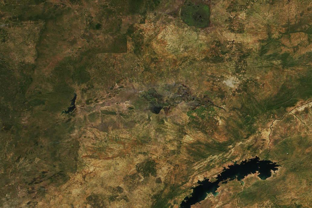 Satellite view of mixed brown and green covered land. The Kafue River and Lake Manyeke center, and show especially dry and craggy land around their banks.