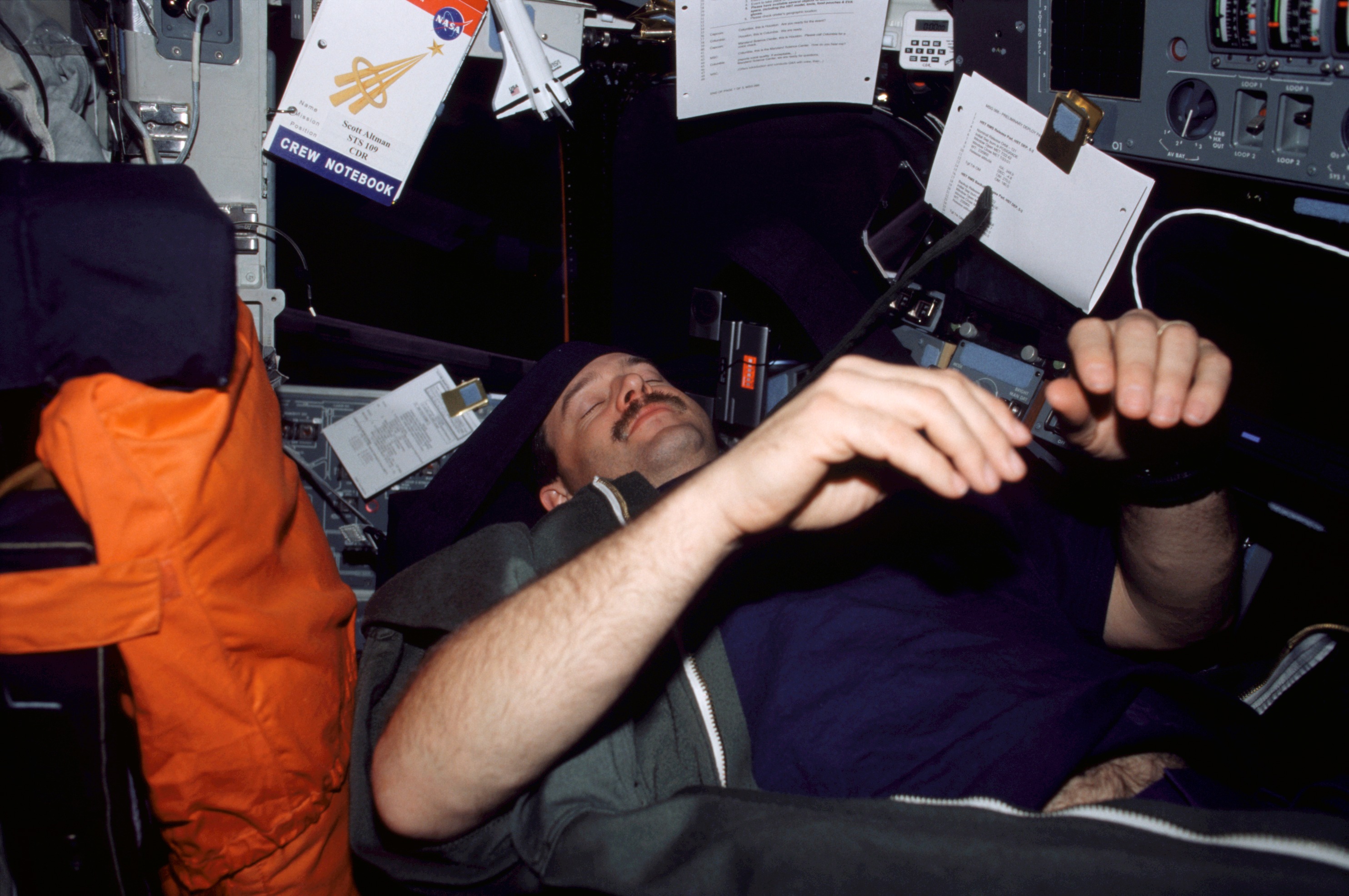 An astronaut sleeps on the space shuttle