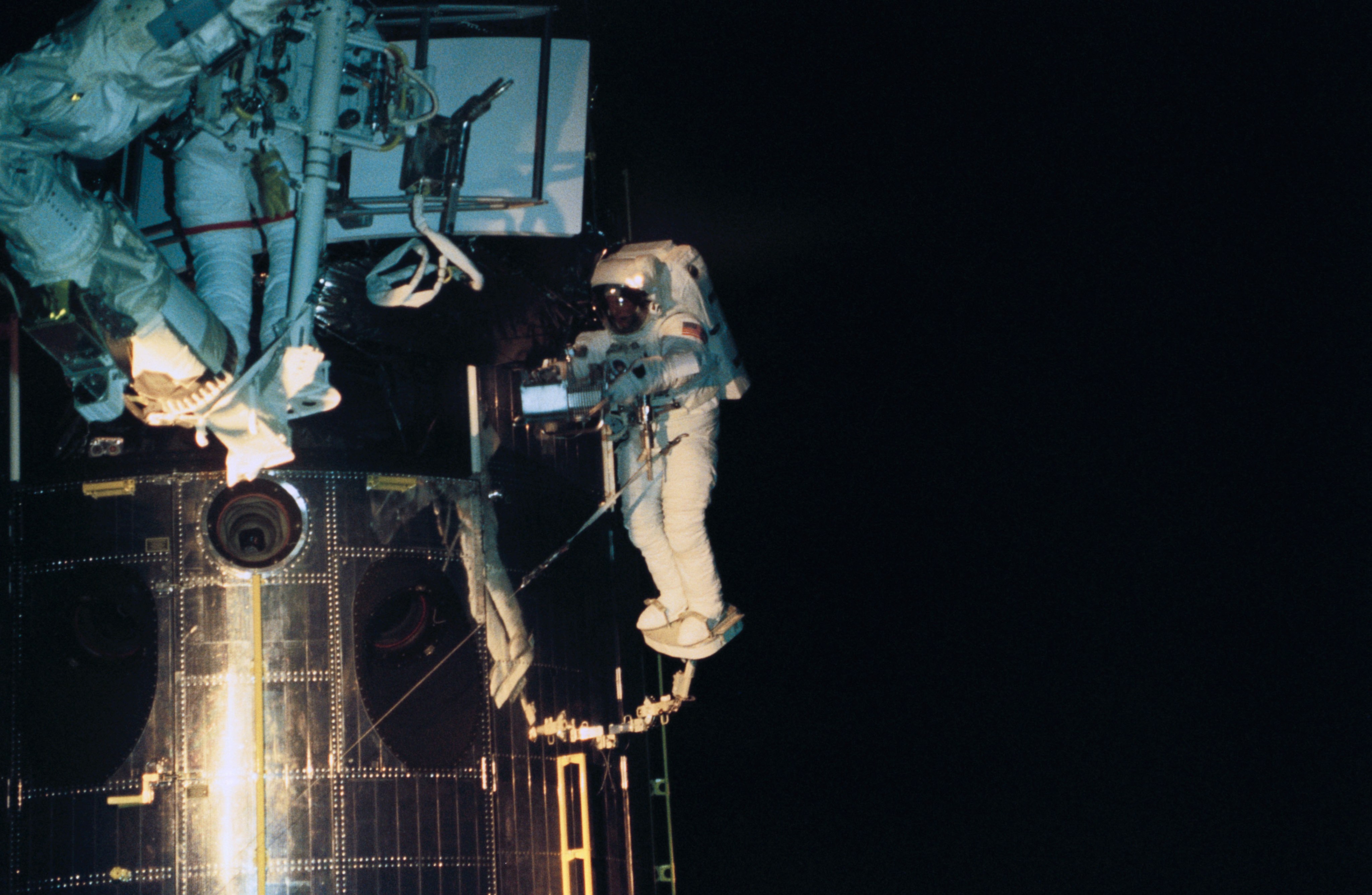Two astronauts remove an instrument from Hubble