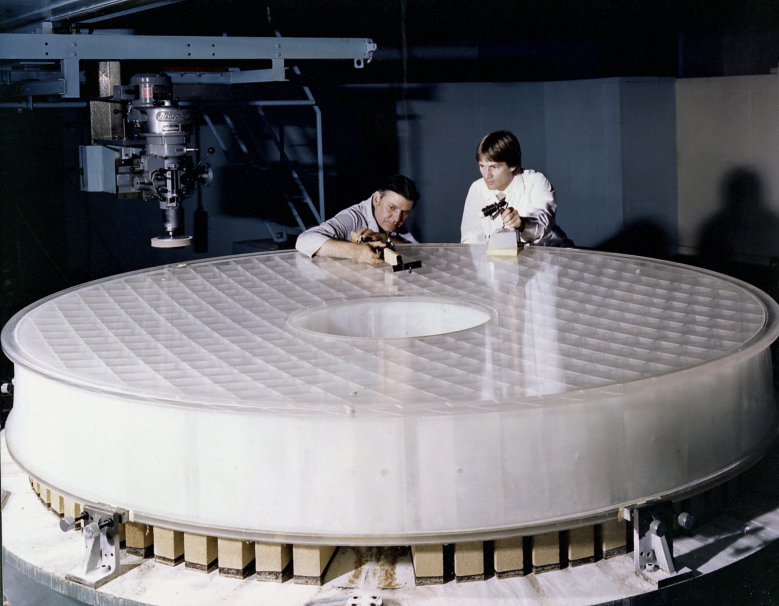Two engineers inspect the primary mirror of Hubble.