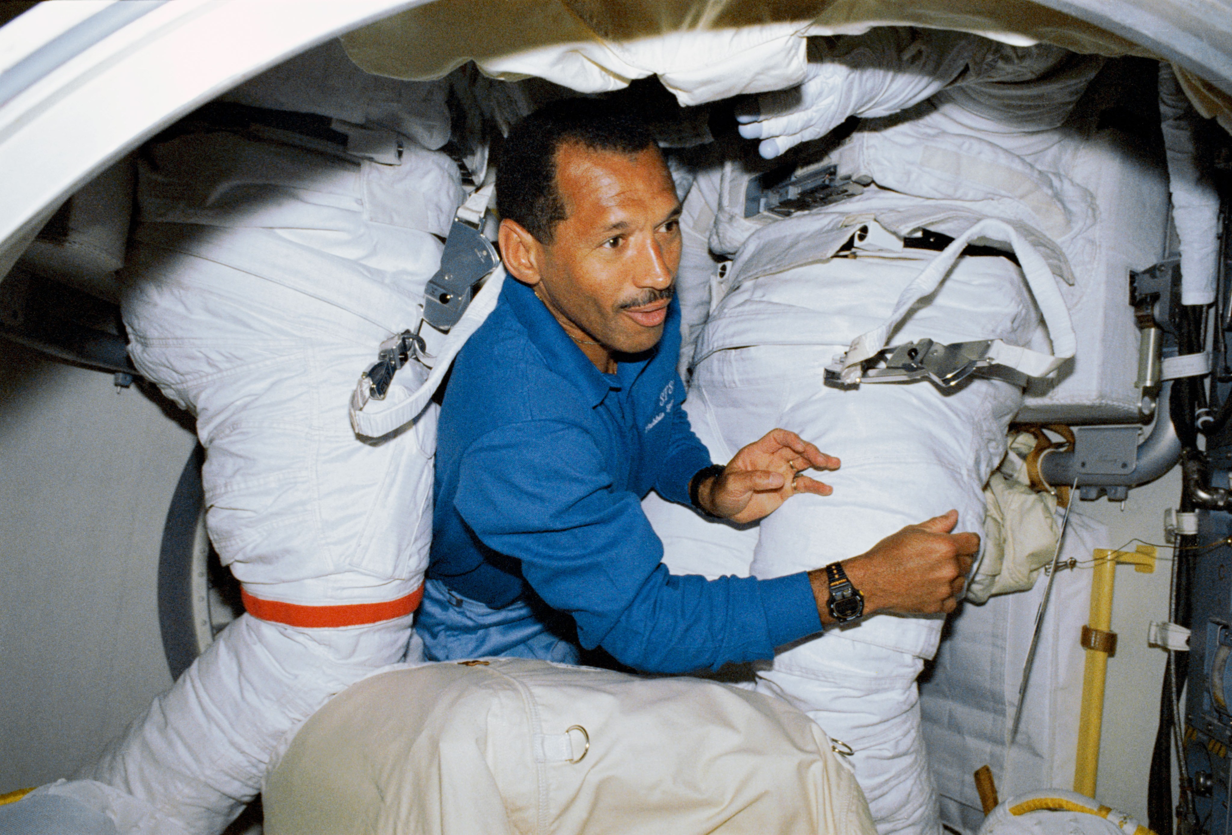 An astronaut surrounded by space suits in the airlock.