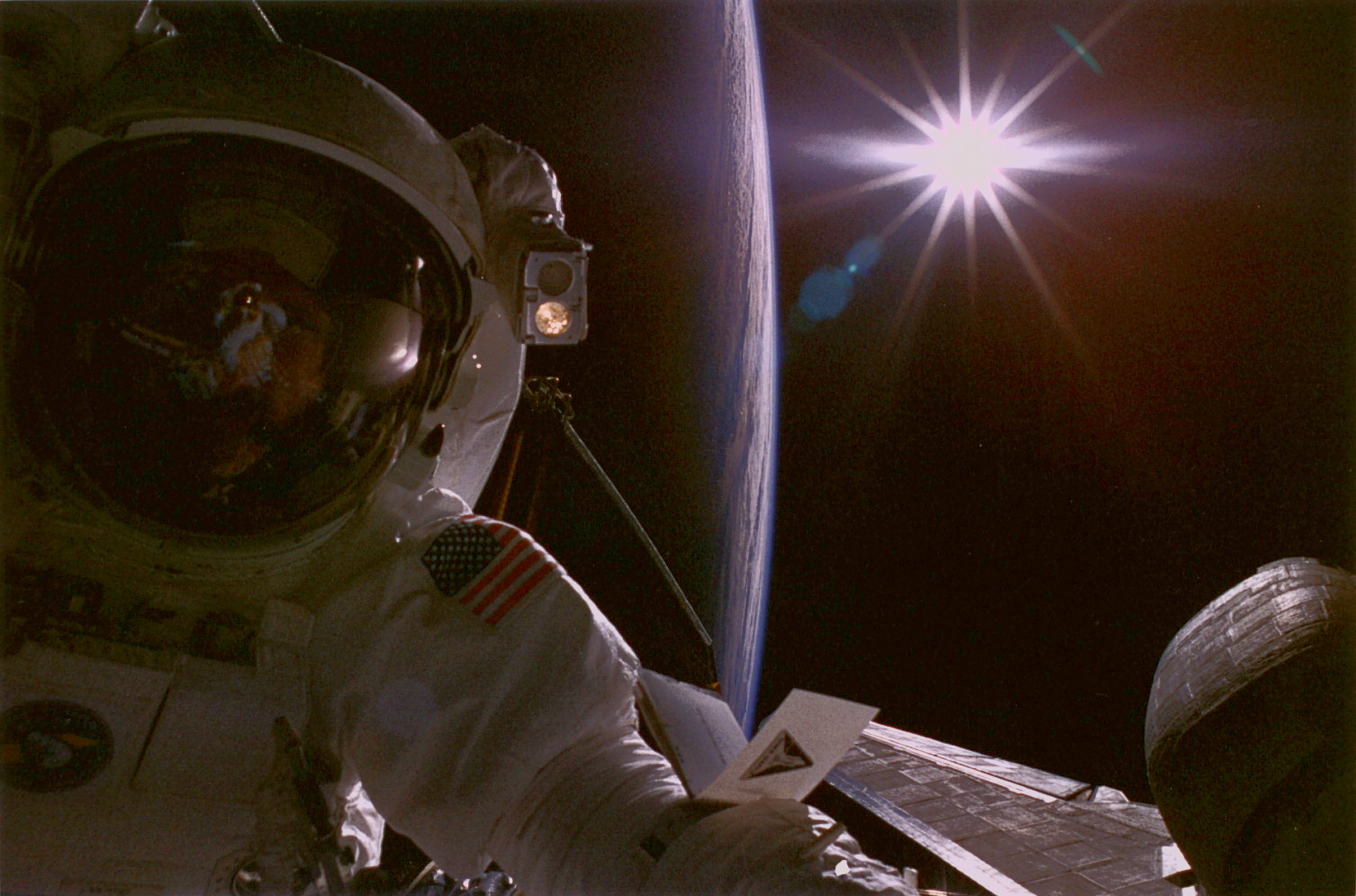 An astronaut with the earth and sun in the background.