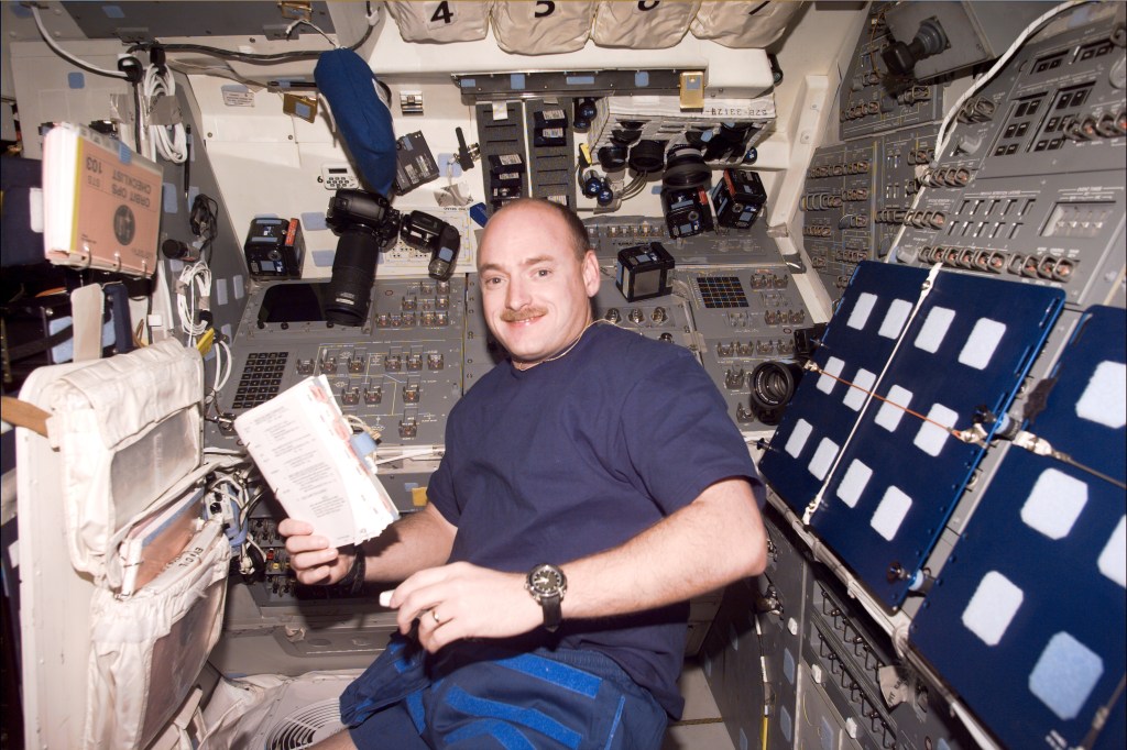 An astronaut floats in the flight deck of the Shuttle and smiles for the camera.