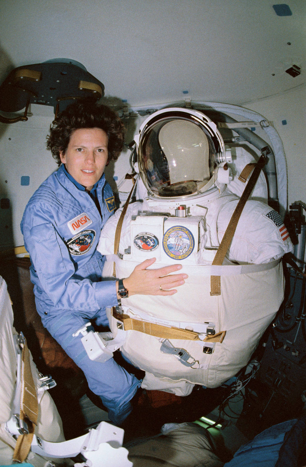 An astronaut next to her spacesuit in the crew cabin of the shuttle.