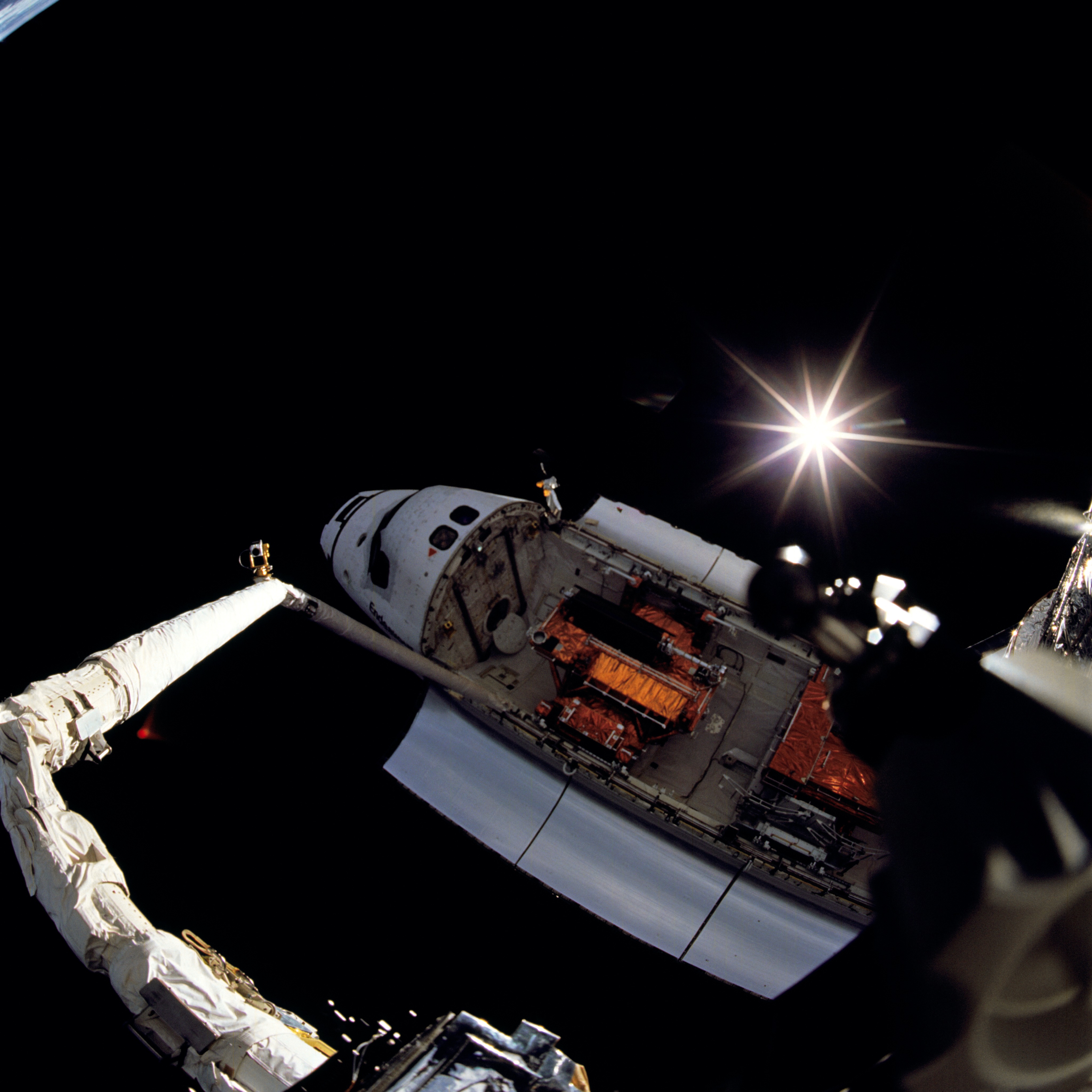 A photo of the Shuttle from above with a rayed sun effect in the background