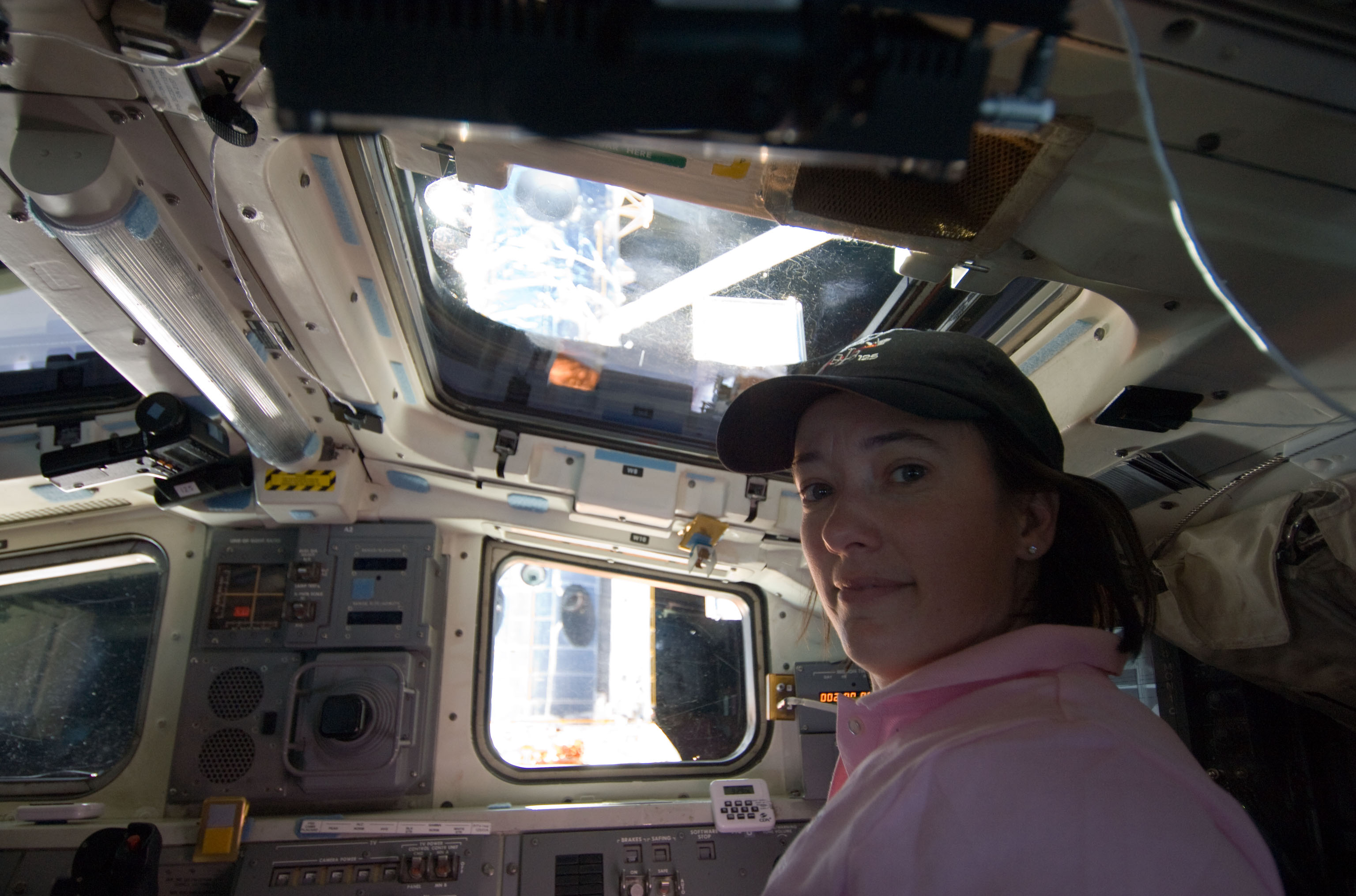An astronaut looks at the camera while at her station working the robotic arm.