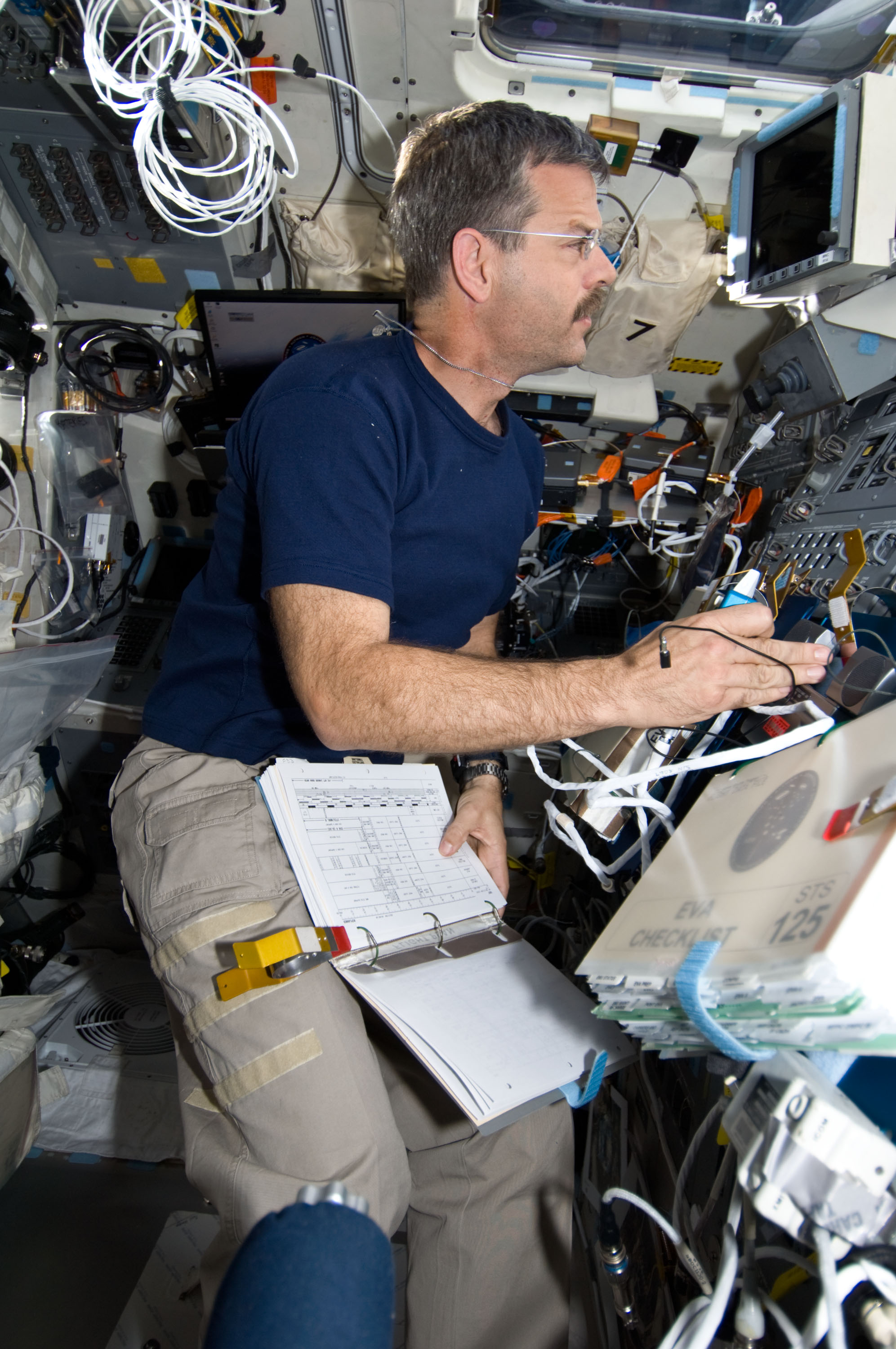 The commander of the mission on the flight deck communicates with the astronauts who are spacewalking.