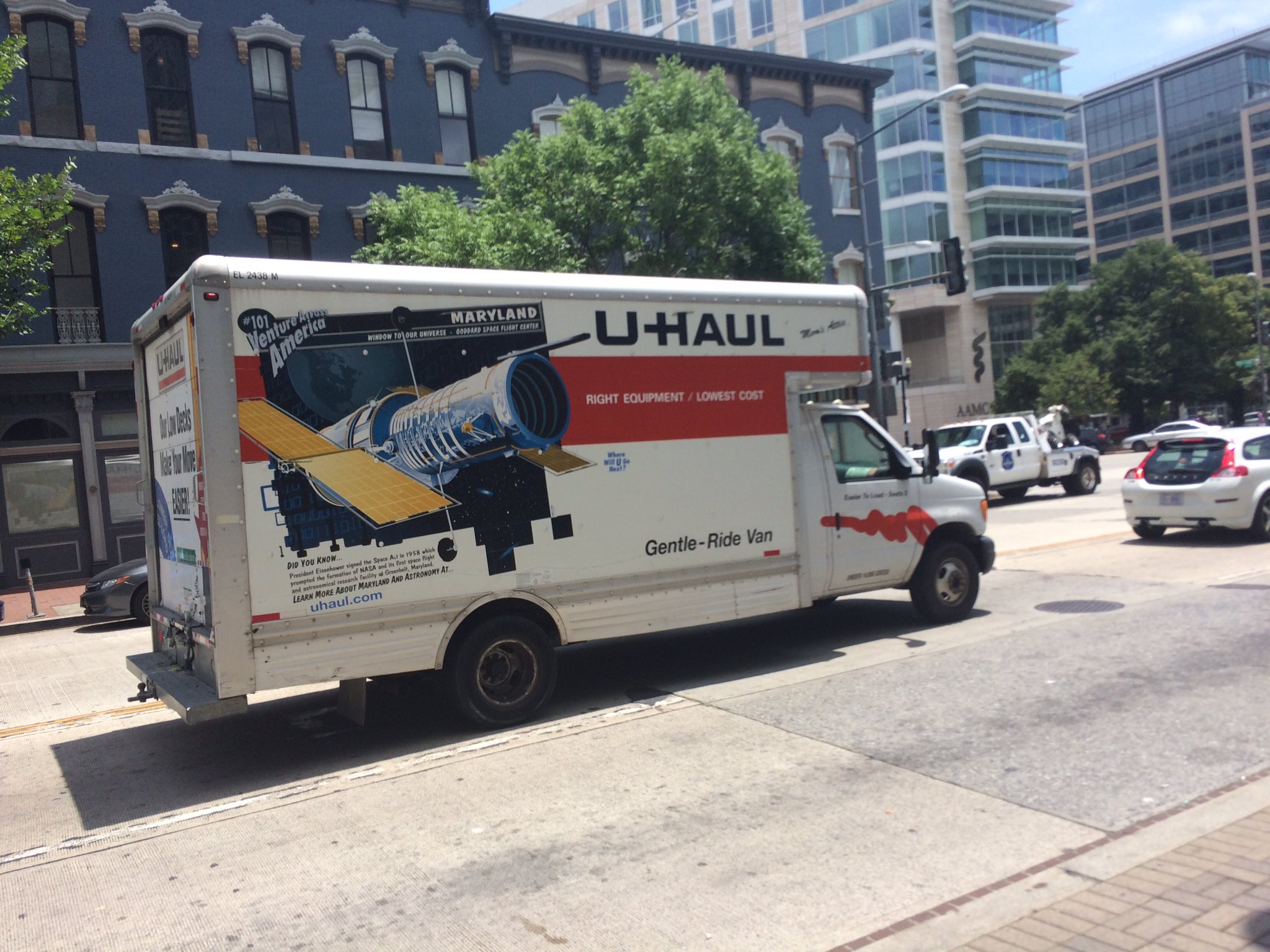 A rental truck on a city street that has a Hubble Space Telescope painted on its side