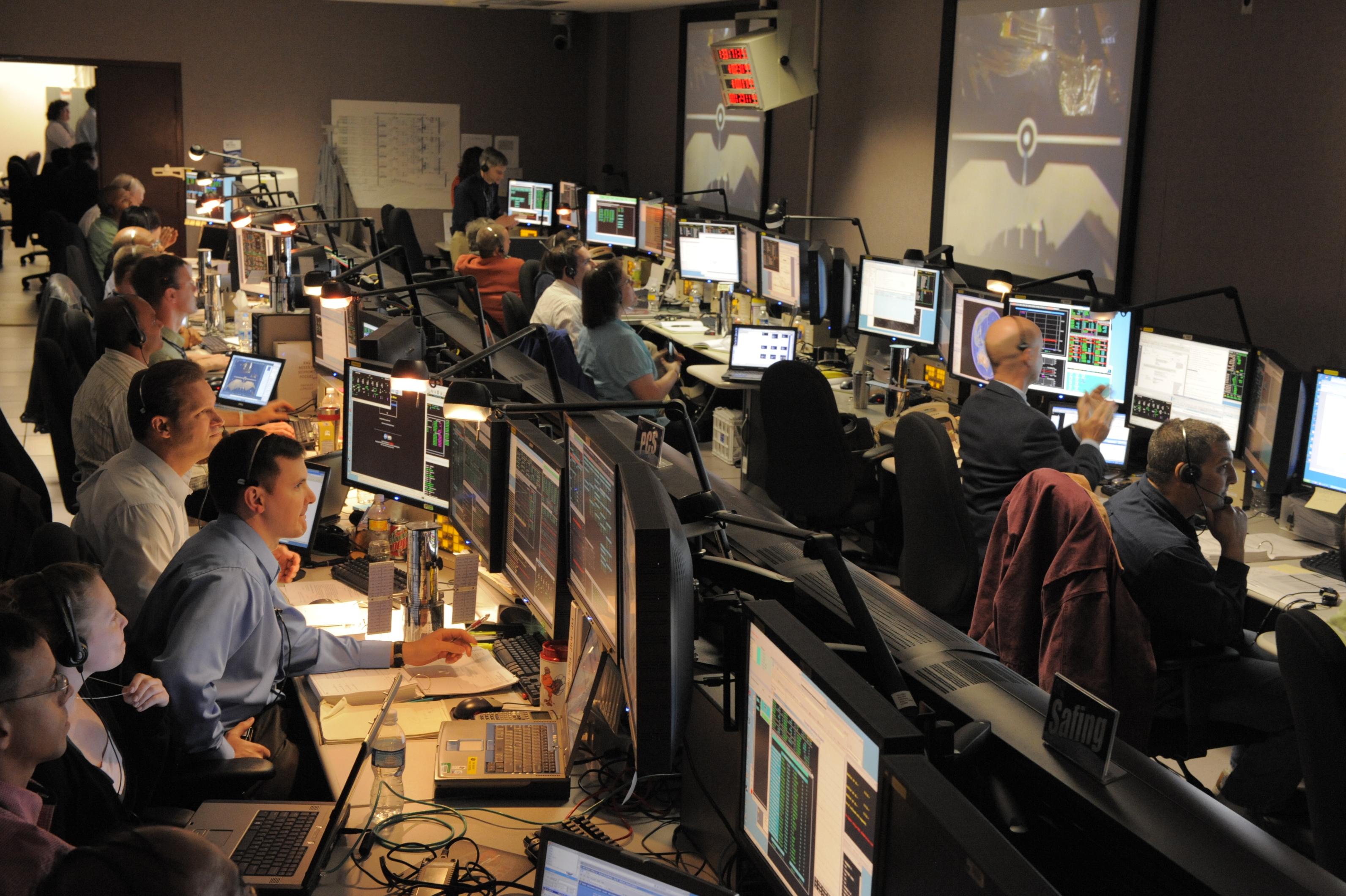Hubble engineers in the control center watch the space shuttle grapple Hubble with its robotic arm.