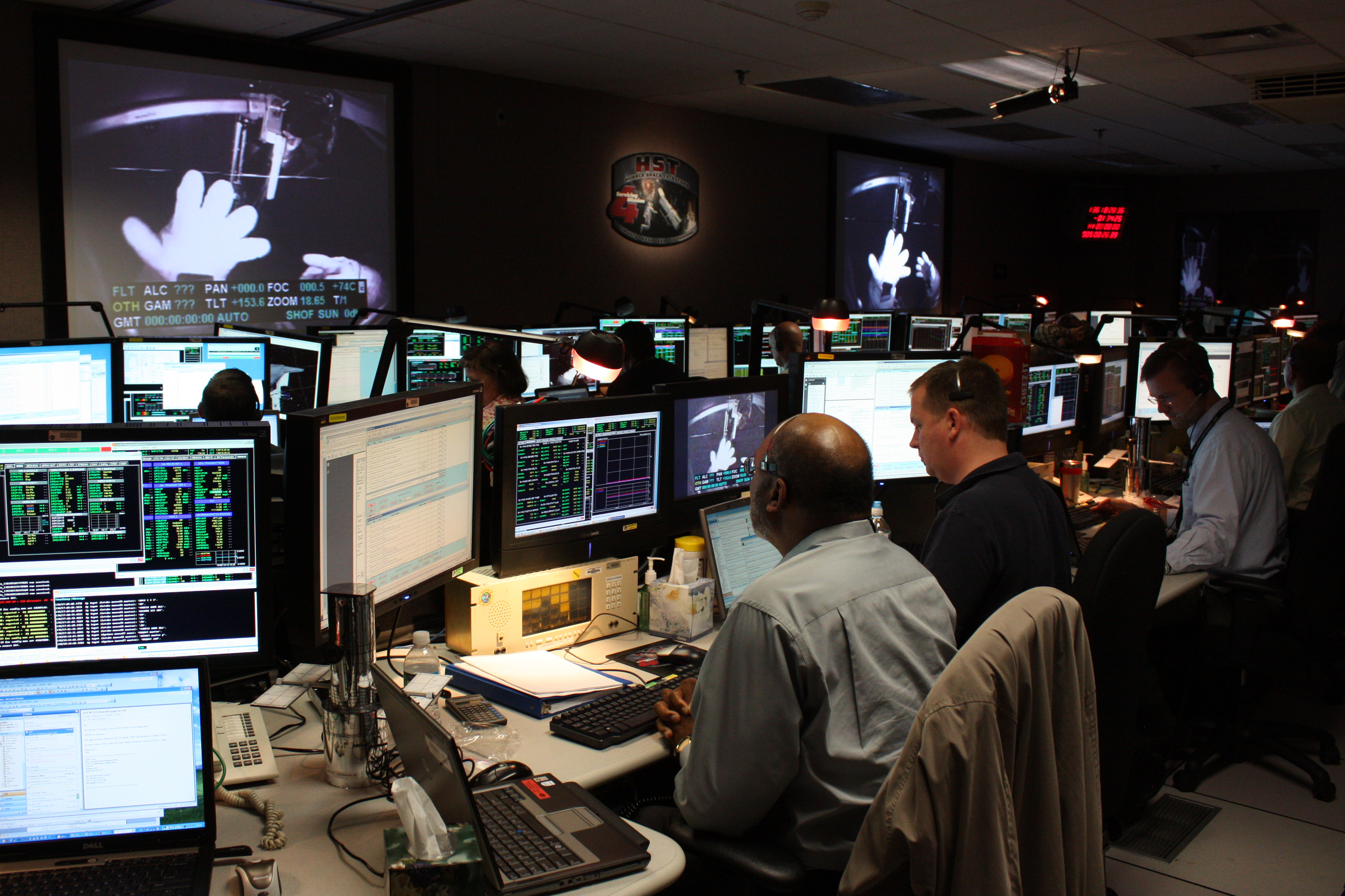 People in the Hubble control center watch the third spacewalk of SM4 on large screen projectors.
