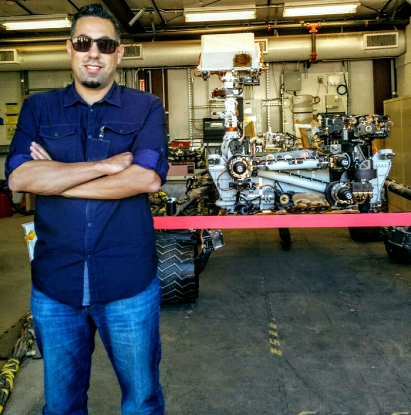 Man standing in front of a Mars rover in garage at JPL.