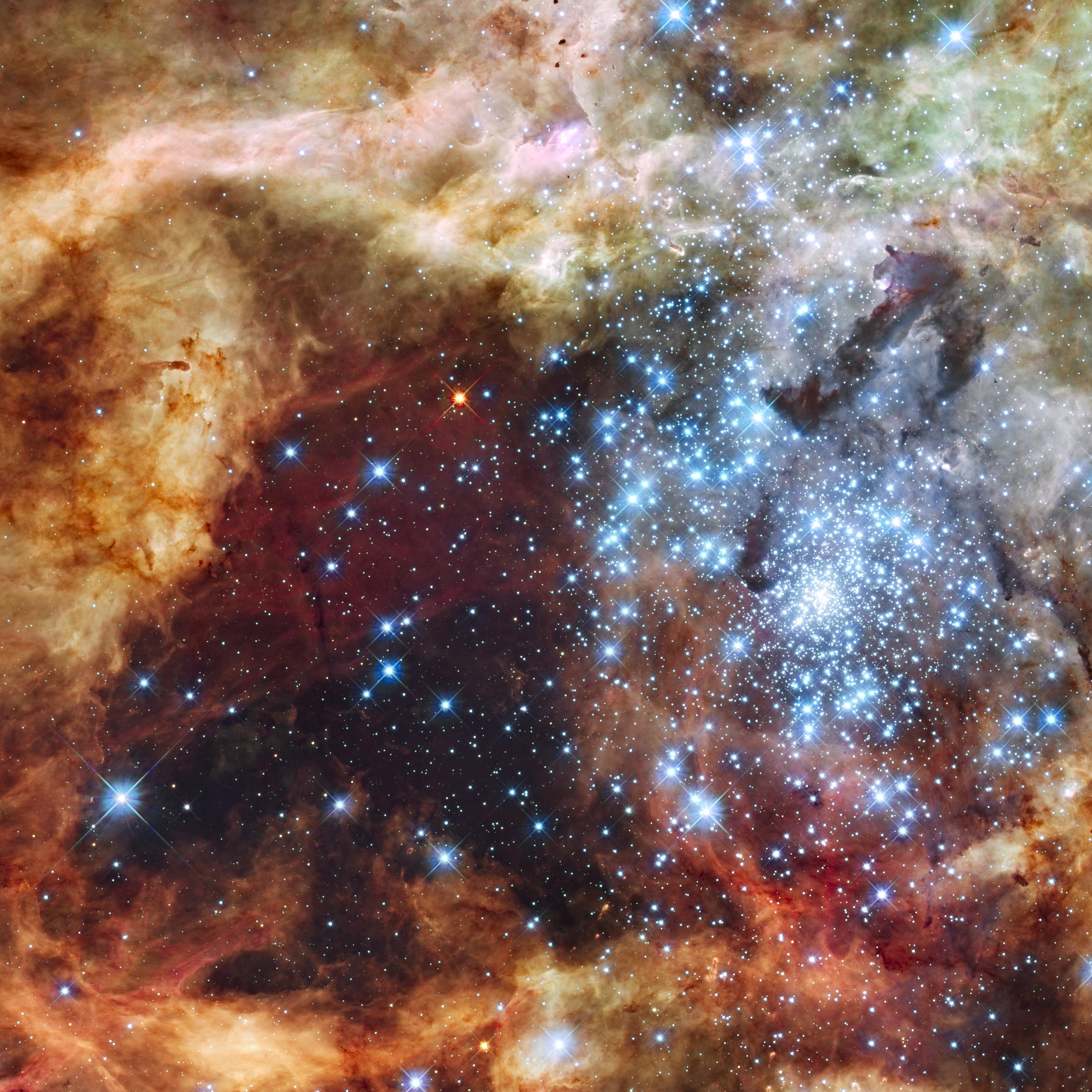 A colorful red, orange, and brown and dust cloud with a bright blue star cluster on the right side.